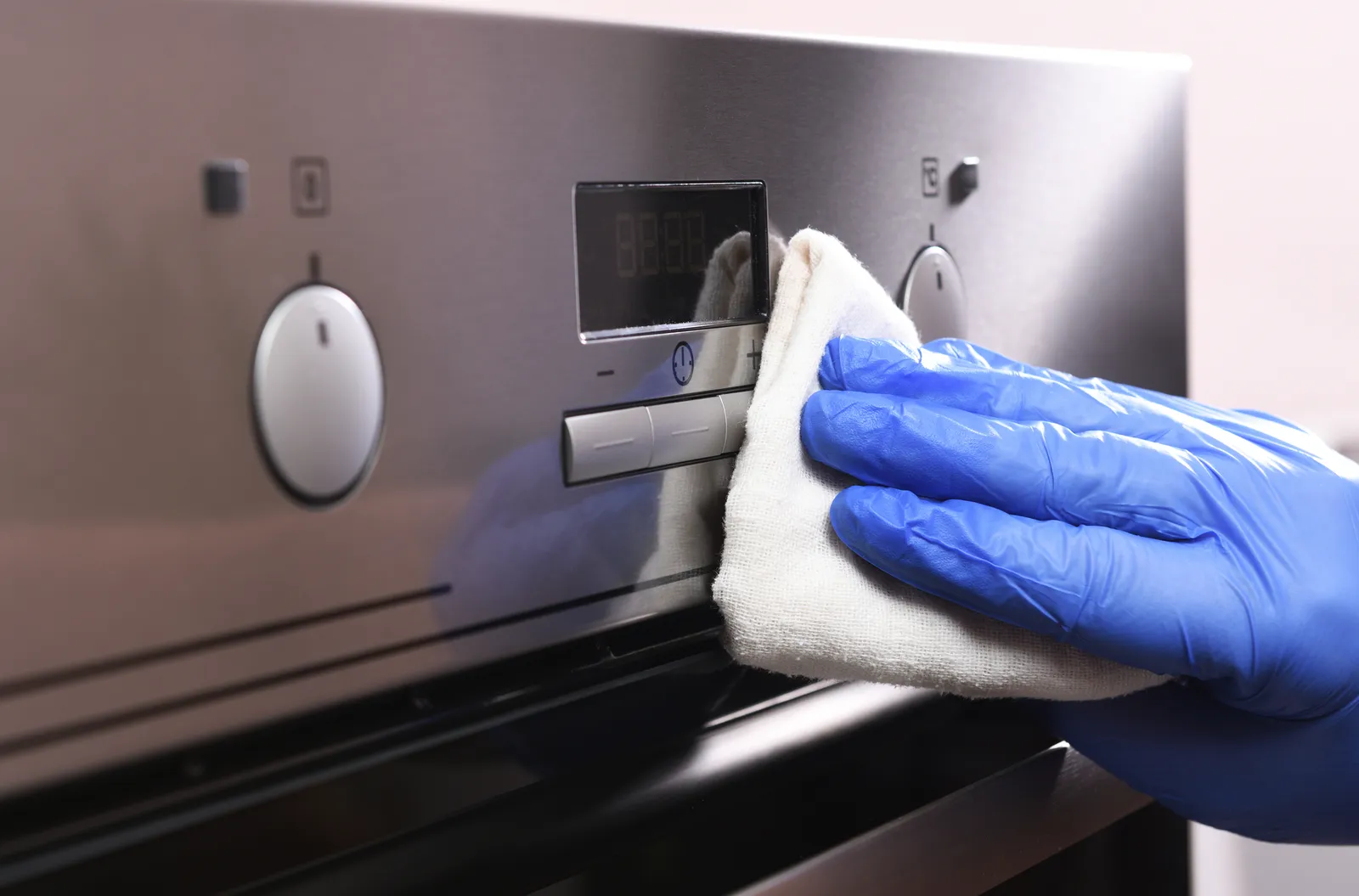 Cleaning the oven outside. A female hand in household cleaning gloves cleans the glass and the oven panel. Disinfection, fight against the virus, coronavirus. General or regular cleaning